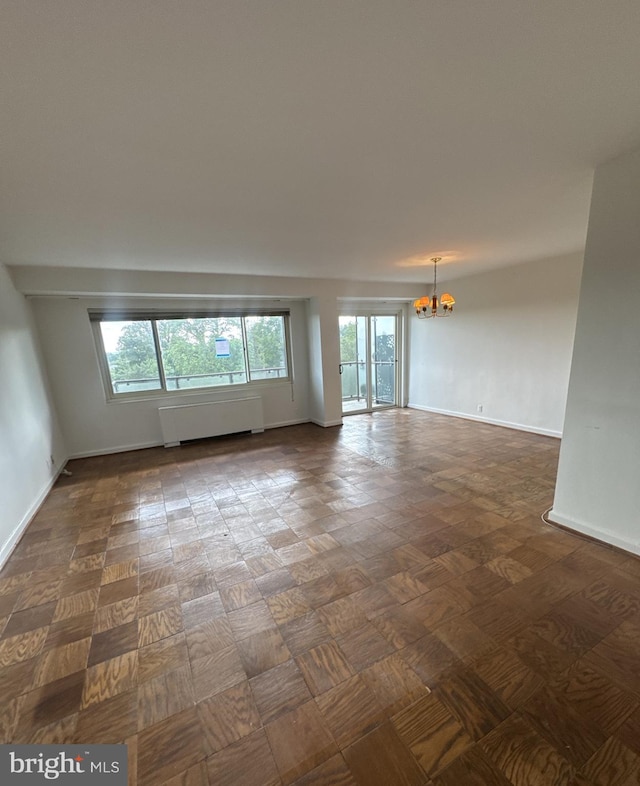 4201 Cathedral Ave NW Unit 1209W, Washington, DC 20016 - empty room with radiator heating unit, a chandelier, healthy amount of natural light, and baseboards