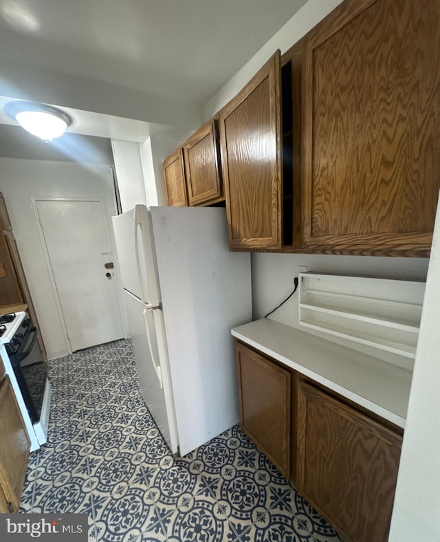 4201 Cathedral Ave NW Unit 1209W, Washington, DC 20016 - kitchen featuring freestanding refrigerator, range, light countertops, and brown cabinetry