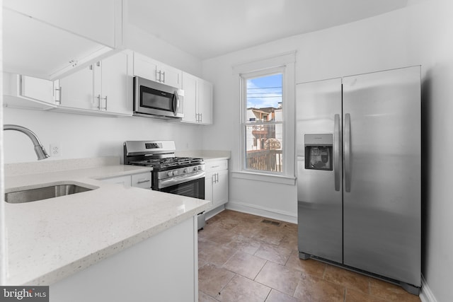 2808 Presstman St, Baltimore, MD 21216 - kitchen with stainless steel appliances, a sink, white cabinetry, light stone countertops, and baseboards