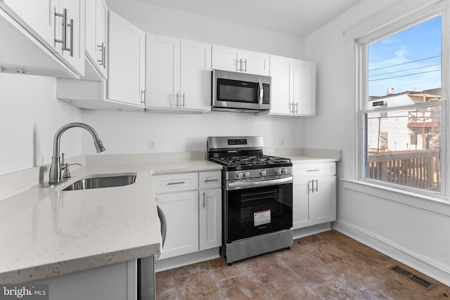2808 Presstman St, Baltimore, MD 21216 - kitchen featuring appliances with stainless steel finishes, a sink, white cabinetry, light stone countertops, and baseboards
