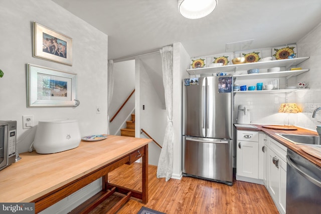206 Mountain Rd, Linthicum Heights, MD 21090 - kitchen featuring appliances with stainless steel finishes, a sink, white cabinets, light wood-type flooring, and decorative backsplash