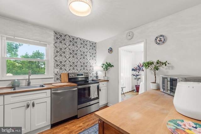 206 Mountain Rd, Linthicum Heights, MD 21090 - kitchen with a sink, appliances with stainless steel finishes, white cabinets, wooden counters, and light wood-type flooring