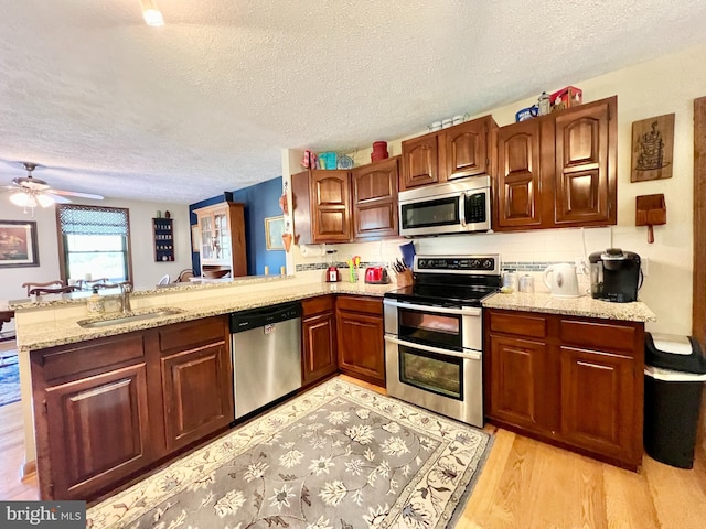 299 Valentine Acres Rd, Clearville, PA 15535 - kitchen with stainless steel appliances, a sink, a textured ceiling, a peninsula, and light wood-type flooring