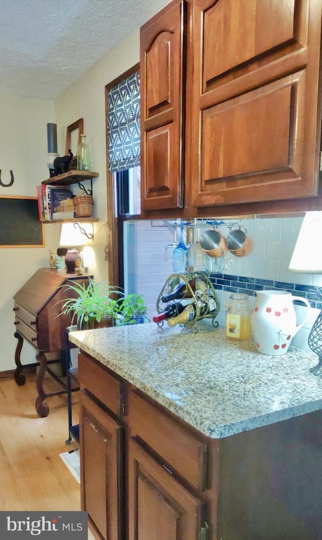 299 Valentine Acres Rd, Clearville, PA 15535 - kitchen with light wood-style flooring, light stone countertops, tasteful backsplash, brown cabinetry, and a textured ceiling