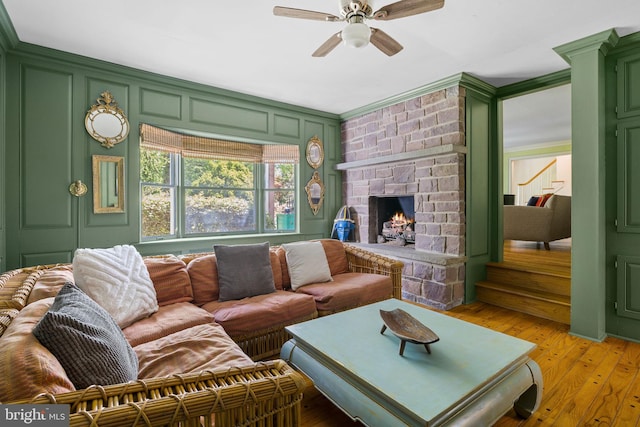 65 Covered Bridge Rd, New Hope, PA 18938 - living room featuring a ceiling fan, a stone fireplace, light wood-style flooring, and a decorative wall