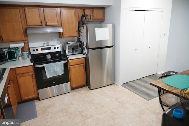 9 Wyndham Ct, Downingtown, PA 19335 - kitchen featuring appliances with stainless steel finishes, under cabinet range hood, brown cabinetry, and light countertops