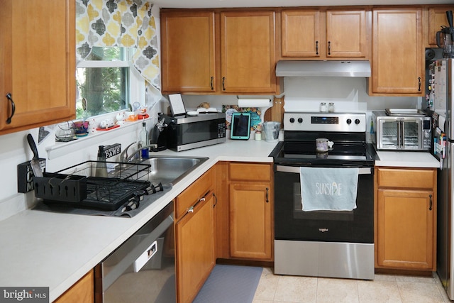 9 Wyndham Ct, Downingtown, PA 19335 - kitchen with appliances with stainless steel finishes, under cabinet range hood, light countertops, brown cabinetry, and a sink