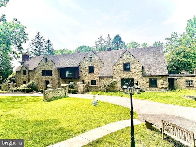 1319 Remington Rd, Wynnewood, PA 19096 - tudor-style house with stone siding, a front yard, and a chimney