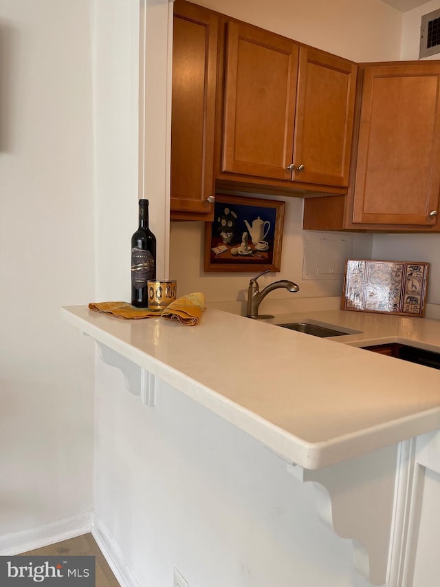 510 N Street Street SW Unit N223, Washington, DC 20024 - kitchen with brown cabinets, a sink, light countertops, a kitchen bar, and baseboards