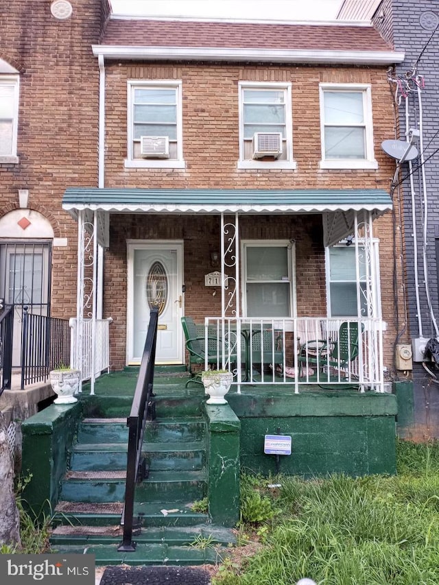 712 Hamlin St NE, Washington, DC 20017 - townhome / multi-family property with brick siding, covered porch, roof with shingles, and cooling unit