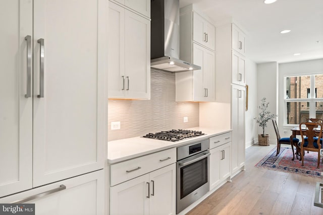 3546 Sutton Heights Cir, Fairfax, VA 22031 - kitchen with stainless steel appliances, wall chimney exhaust hood, tasteful backsplash, light countertops, and light wood finished floors