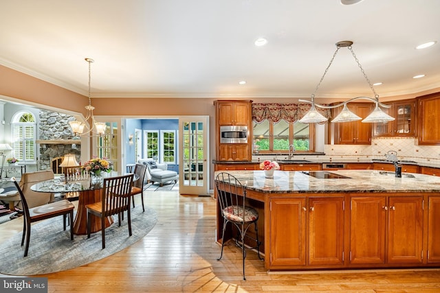 1217 Tullamore Cir, Chester Springs, PA 19425 - kitchen with stainless steel microwave, brown cabinets, stone countertops, healthy amount of natural light, and crown molding