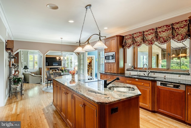 1217 Tullamore Cir, Chester Springs, PA 19425 - kitchen with brown cabinets, a kitchen island with sink, dark stone counters, healthy amount of natural light, and ornamental molding