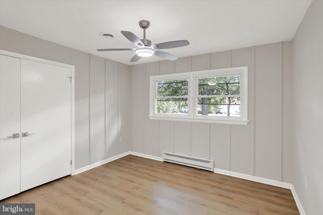1216 Steamboat Rd, Shady Side, MD 20764 - unfurnished bedroom with baseboard heating, light wood-style flooring, a decorative wall, a ceiling fan, and a closet