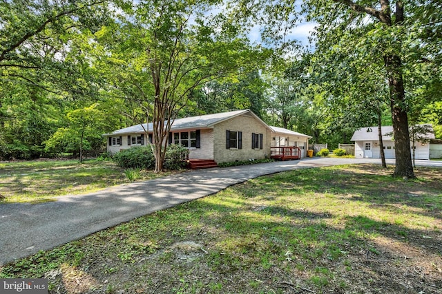 1216 Steamboat Rd, Shady Side, MD 20764 - ranch-style house with asphalt driveway, brick siding, a front yard, view of wooded area, and an outdoor structure