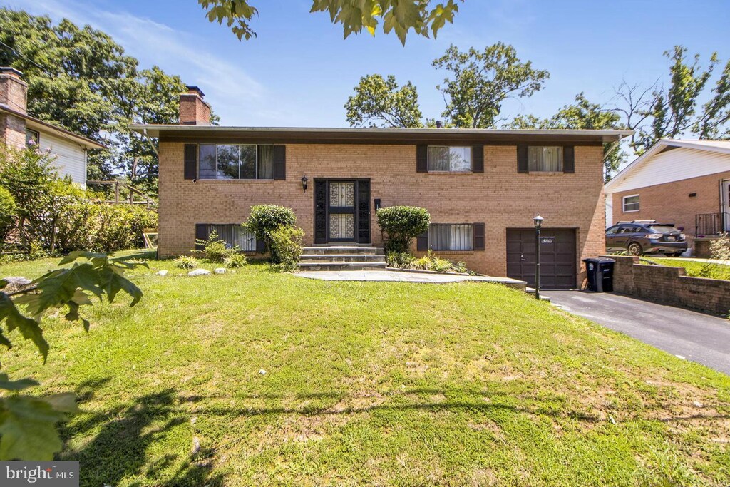 6311 Barrs Ln, Lanham, MD 20706 - bi-level home with driveway, a chimney, brick siding, a garage, and a front yard