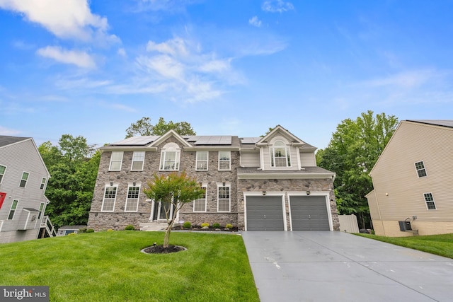 7027 Sand Cherry Way, Clinton, MD 20735 - view of front of home with driveway, roof mounted solar panels, a front yard, stone siding, and a garage