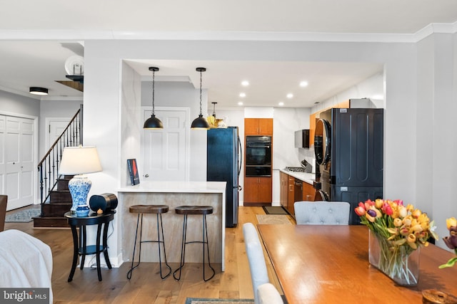 2700 Virginia Ave NW Unit 109, Washington, DC 20037 - kitchen featuring appliances with stainless steel finishes, a warming drawer, light wood-style floors, a breakfast bar, and a peninsula