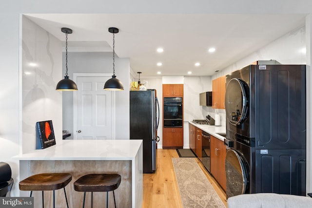 2700 Virginia Ave NW Unit 109, Washington, DC 20037 - kitchen featuring stacked washer and clothes dryer, black appliances, a warming drawer, light wood finished floors, and a peninsula