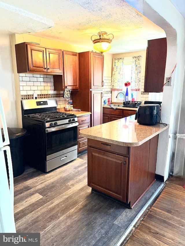 3141 S Atlanta Rd, Camden, NJ 08104 - kitchen with stainless steel gas stove, light countertops, dark wood-style floors, backsplash, and a peninsula