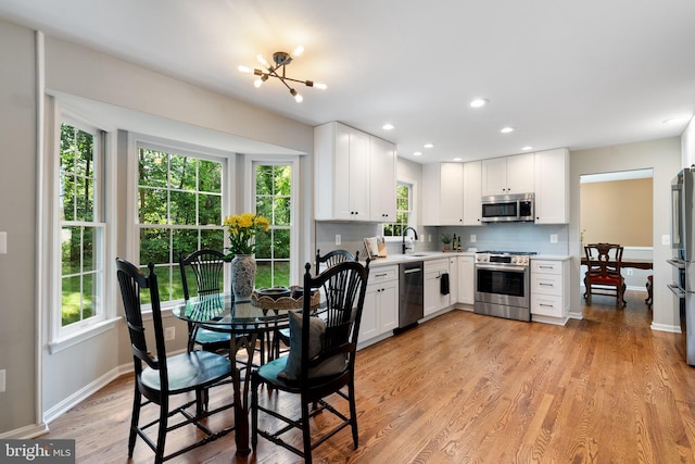 43952 Bidwell Ct, Ashburn, VA 20147 - kitchen featuring appliances with stainless steel finishes, white cabinets, light countertops, light wood-style floors, and tasteful backsplash