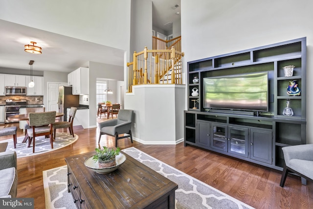 17542 Falls Pl, Round Hill, VA 20141 - living room featuring a towering ceiling, dark wood-style flooring, stairs, and baseboards