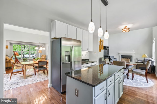 17542 Falls Pl, Round Hill, VA 20141 - kitchen with stainless steel fridge, hardwood / wood-style flooring, a fireplace, a center island, and dark stone countertops