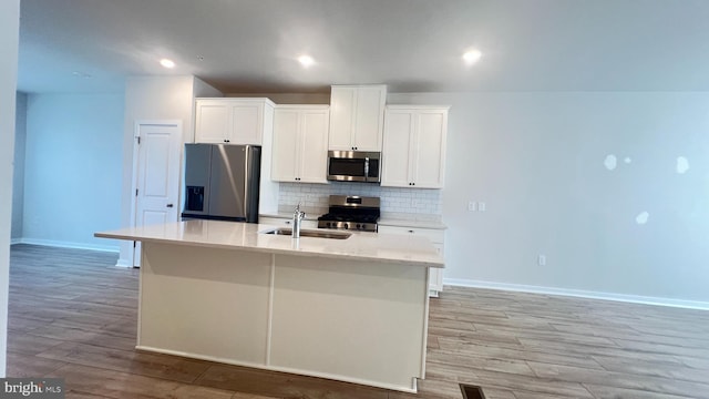 4904 Brookside Ct, Coopersburg, PA 18036 - kitchen with appliances with stainless steel finishes, a sink, decorative backsplash, light wood-style flooring, and a kitchen island with sink