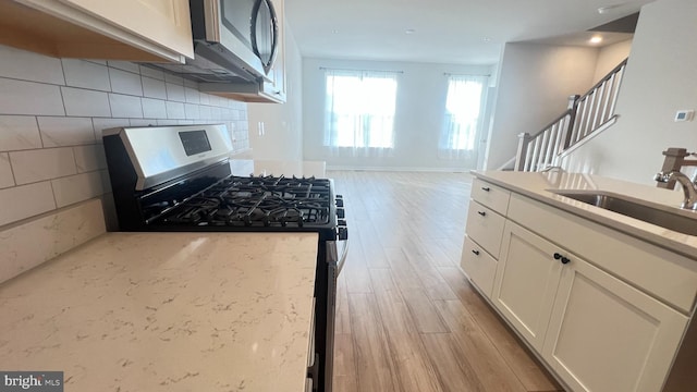 4904 Brookside Ct, Coopersburg, PA 18036 - kitchen with appliances with stainless steel finishes, light wood-style floors, a sink, white cabinets, and backsplash