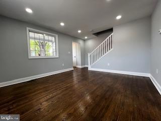13 53rd Pl SE, Washington, DC 20019 - unfurnished living room with stairway, dark wood finished floors, baseboards, and recessed lighting