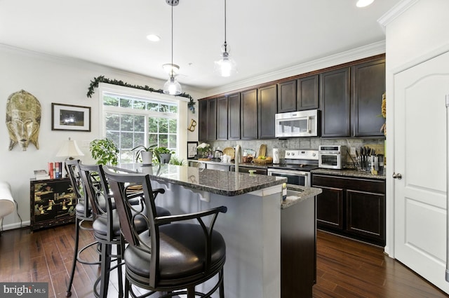 135 Jacobia Dr Unit H-3, Pasadena, MD 21122 - kitchen featuring stainless steel appliances, dark stone countertops, decorative backsplash, a center island, and a kitchen bar