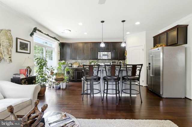 135 Jacobia Dr Unit H-3, Pasadena, MD 21122 - kitchen featuring stainless steel appliances, a breakfast bar area, dark brown cabinetry, a center island with sink, and ornamental molding
