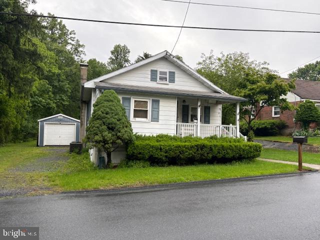 5009 Forest Ave, Temple, PA 19560 - bungalow-style house with an outdoor structure, covered porch, a detached garage, asphalt driveway, and a chimney
