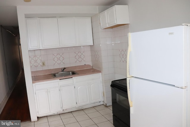 1501 Druid Hill Ave, Baltimore, MD 21217 - kitchen with freestanding refrigerator, black electric range, a sink, white cabinets, and light countertops