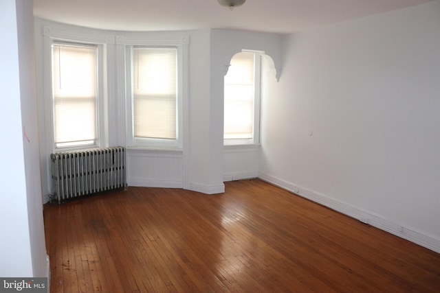 1501 Druid Hill Ave, Baltimore, MD 21217 - spare room featuring radiator, arched walkways, wood-type flooring, and baseboards