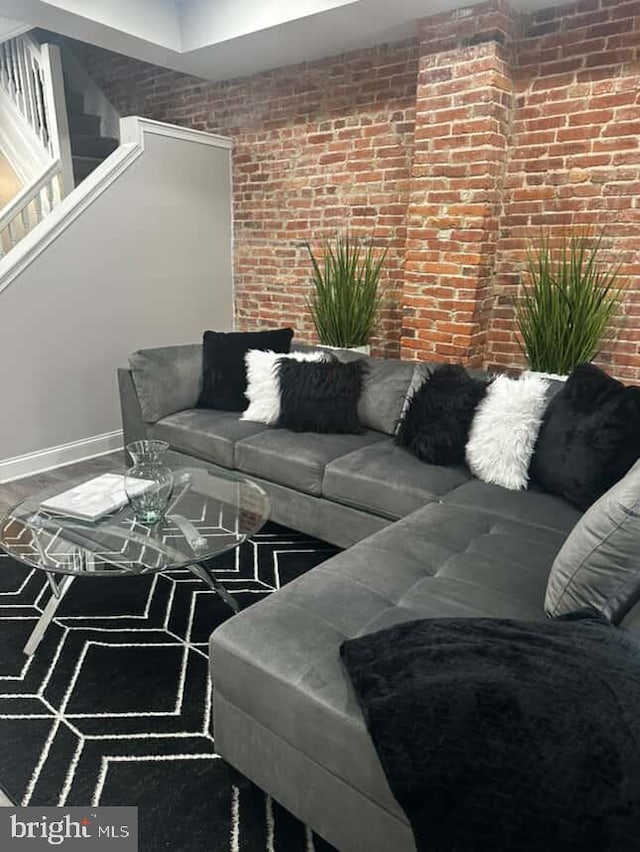 1528 N Ellamont St, Baltimore, MD 21216 - living area with brick wall, stairs, and baseboards