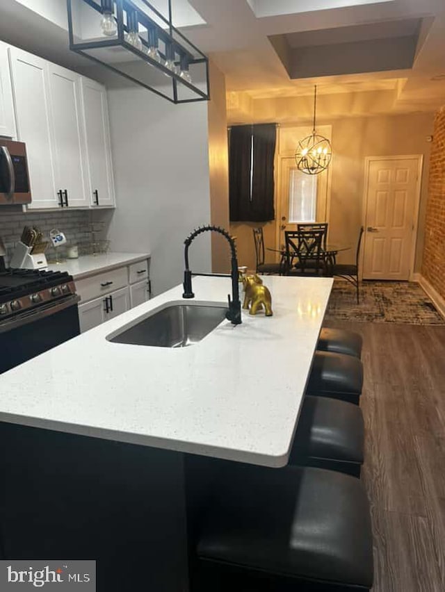 1528 N Ellamont St, Baltimore, MD 21216 - kitchen with a sink, appliances with stainless steel finishes, white cabinetry, dark wood finished floors, and tasteful backsplash