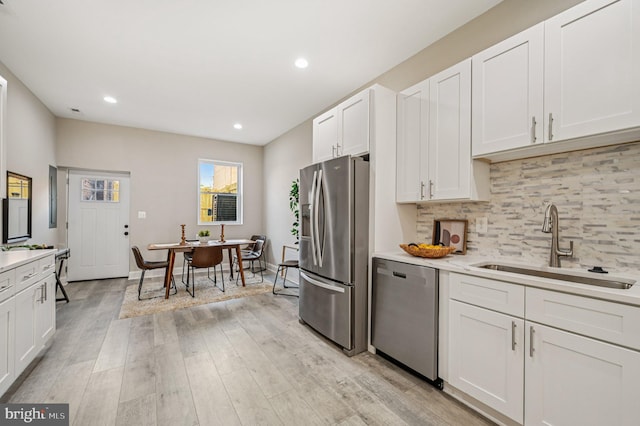 518 N Patterson Park Ave, Baltimore, MD 21205 - kitchen featuring stainless steel appliances, a sink, light countertops, backsplash, and light wood finished floors