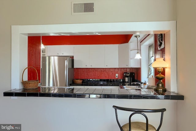 896 Hershey Heights Rd, Hanover, PA 17331 - kitchen featuring freestanding refrigerator, tile counters, decorative backsplash, white cabinets, and a peninsula