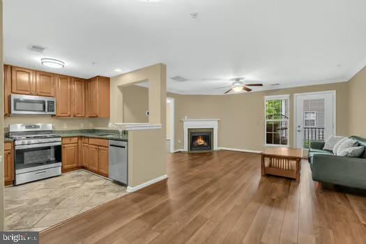45472 Westmeath Way Unit I 12, Great Mills, MD 20634 - kitchen featuring stainless steel appliances, open floor plan, a ceiling fan, a warm lit fireplace, and light wood-style flooring