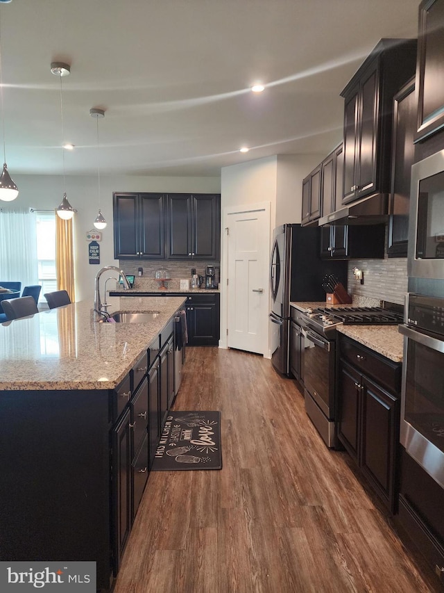 114 Furies St, Smyrna, DE 19977 - kitchen featuring a sink, stainless steel appliances, decorative backsplash, light stone countertops, and a center island with sink