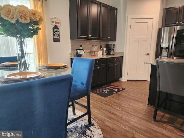 114 Furies St, Smyrna, DE 19977 - kitchen featuring stainless steel refrigerator with ice dispenser, backsplash, light wood-style floors, light stone counters, and dark brown cabinets
