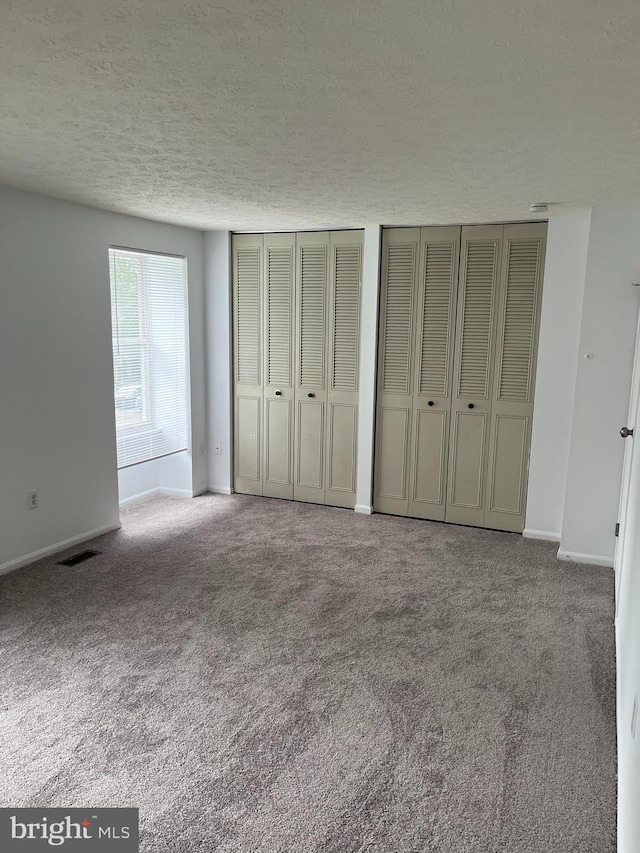7539 Rain Flower Way, Columbia, MD 21046 - unfurnished bedroom with a textured ceiling, multiple closets, and carpet flooring