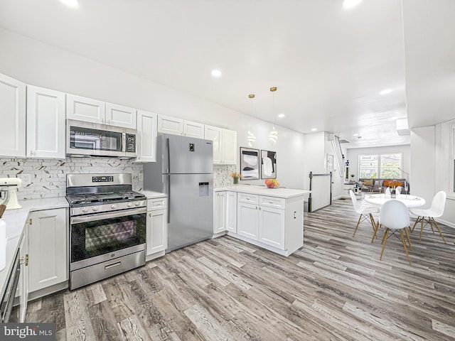 5849 Washington Ave, Philadelphia, PA 19143 - kitchen featuring appliances with stainless steel finishes, light countertops, light wood finished floors, backsplash, and a peninsula