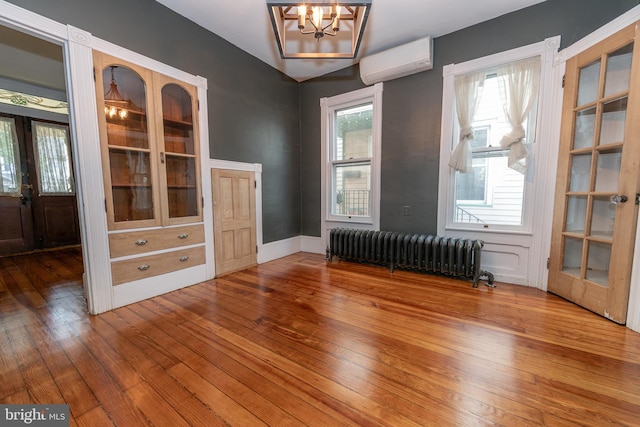 28 Bowen Ave, Woodstown, NJ 08098 - empty room with radiator, a wall unit AC, a chandelier, and wood-type flooring