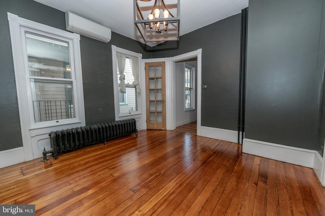 28 Bowen Ave, Woodstown, NJ 08098 - empty room featuring radiator heating unit, a wall mounted AC, a chandelier, hardwood / wood-style flooring, and baseboards