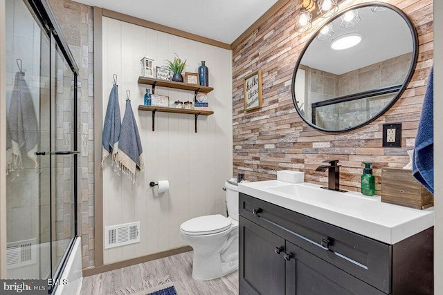 111 Lawrence Dr, Lanoka Harbor, NJ 08734 - bathroom featuring wood walls, toilet, vanity, wood finished floors, and bath / shower combo with glass door