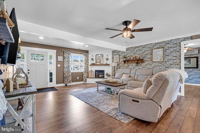 111 Lawrence Dr, Lanoka Harbor, NJ 08734 - living room featuring brick wall, ceiling fan, baseboards, wood-type flooring, and a lit fireplace