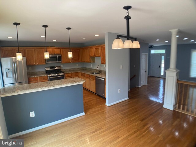 8726 Wadebrook Ter, Springfield, VA 22153 - kitchen with stainless steel appliances, decorative columns, a sink, light wood-style flooring, and brown cabinets