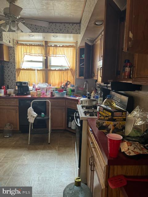 4146 Robbins Ave, Philadelphia, PA 19135 - kitchen featuring ceiling fan, range, wallpapered walls, brown cabinets, and a sink